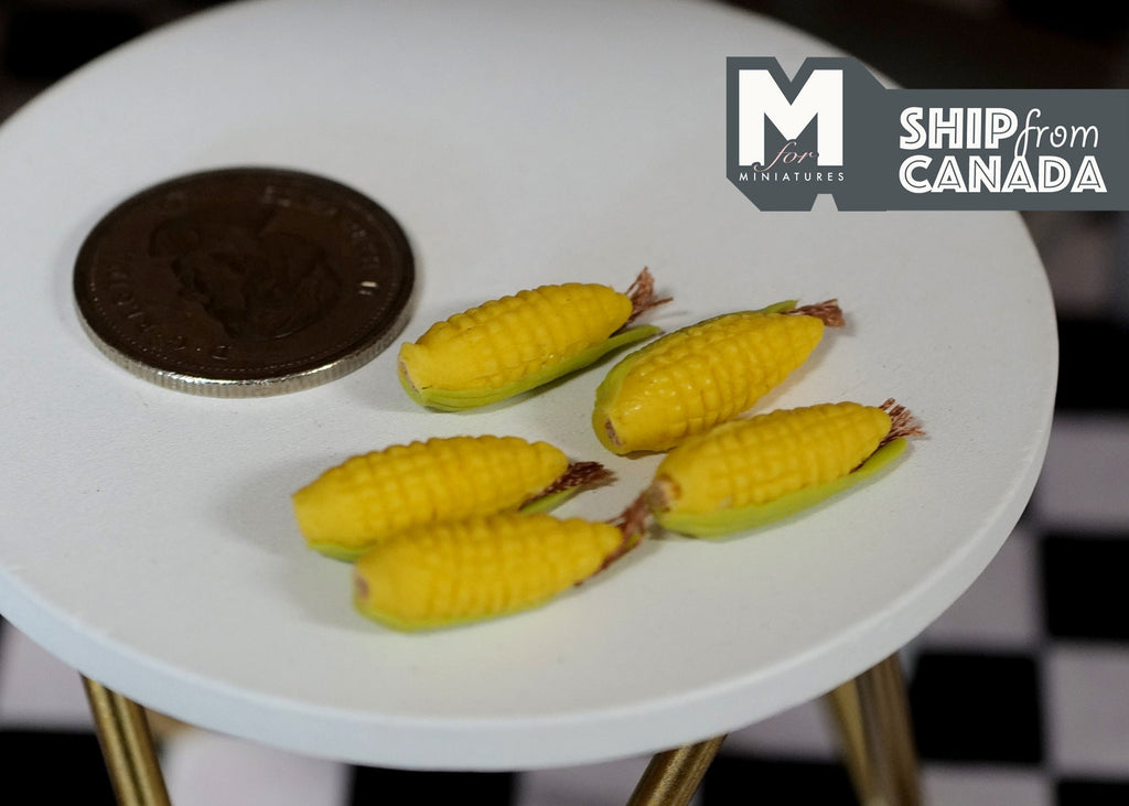 1:12 scale miniature corn cobs, set of 5, yellow corn with husks, shown on a round white table beside a coin
