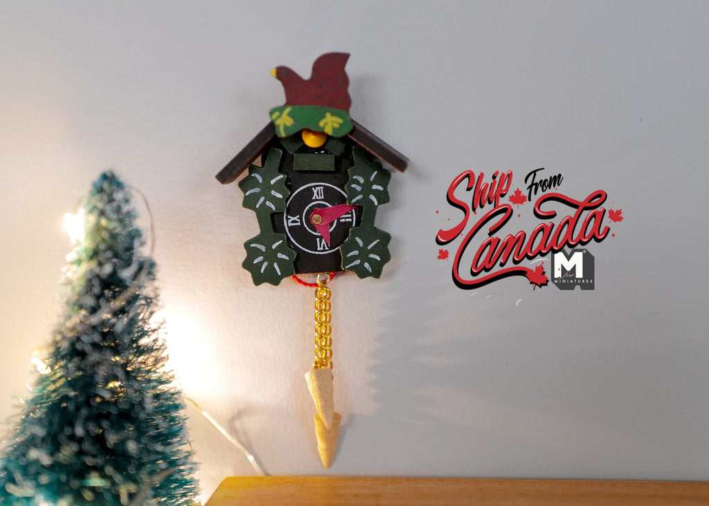 1:12 scale miniature wood cuckoo wall clock in black with pinecone weights and red bird, hung beside a small tree