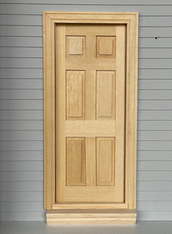 1:12 scale miniature unfinished classic 6 panel interior wood door with back trim, shown set in a gray sided wall