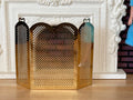 1:12 scale miniature folding fireplace screen in brass with 3 perforated arched panels, at a white fireplace