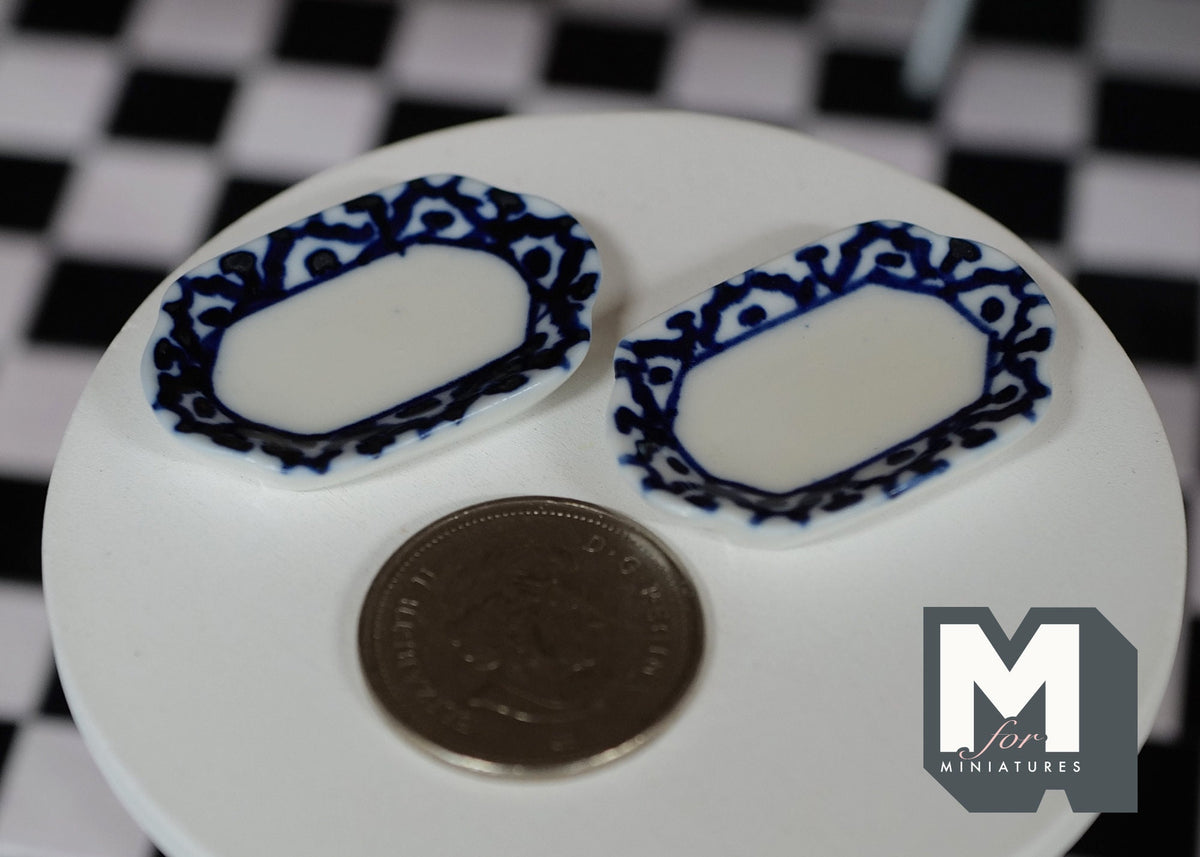 1:12 scale miniature ceramic oval plates with blue scalloped rim, set of 2, shown on a white table beside a coin