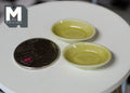 1:12 scale miniature ceramic plates in olive green glaze, set of 2, on a round white table beside a coin for scale