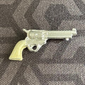 1:12 scale miniature western revolver with cream grip and silver long barrel, non working, on gray fabric