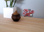 1:12 scale miniature cachepot with lid in aged brown with carved texture, on a wood shelf beside a potted plant
