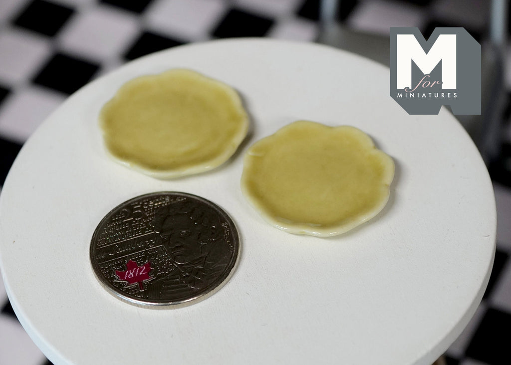 1:12 scale miniature ceramic plates with rim in yellow, set of 2, on a round white table beside a coin for scale