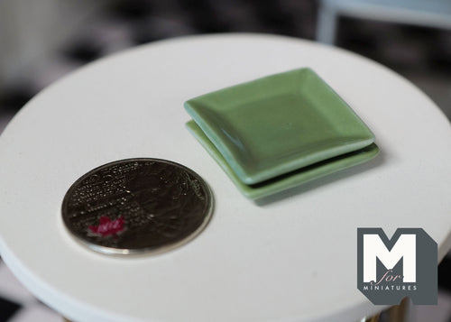 1:12 scale miniature ceramic square plates in celadon green, set of 2, stacked on a white table beside a coin for scale