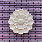 1:12 scale miniature unfinished double layer floral ceiling rose, large, round petal design shown on a purple brick wall