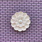 1:12 scale miniature unfinished double layer floral ceiling rose, medium, round petal design shown on a purple brick wall