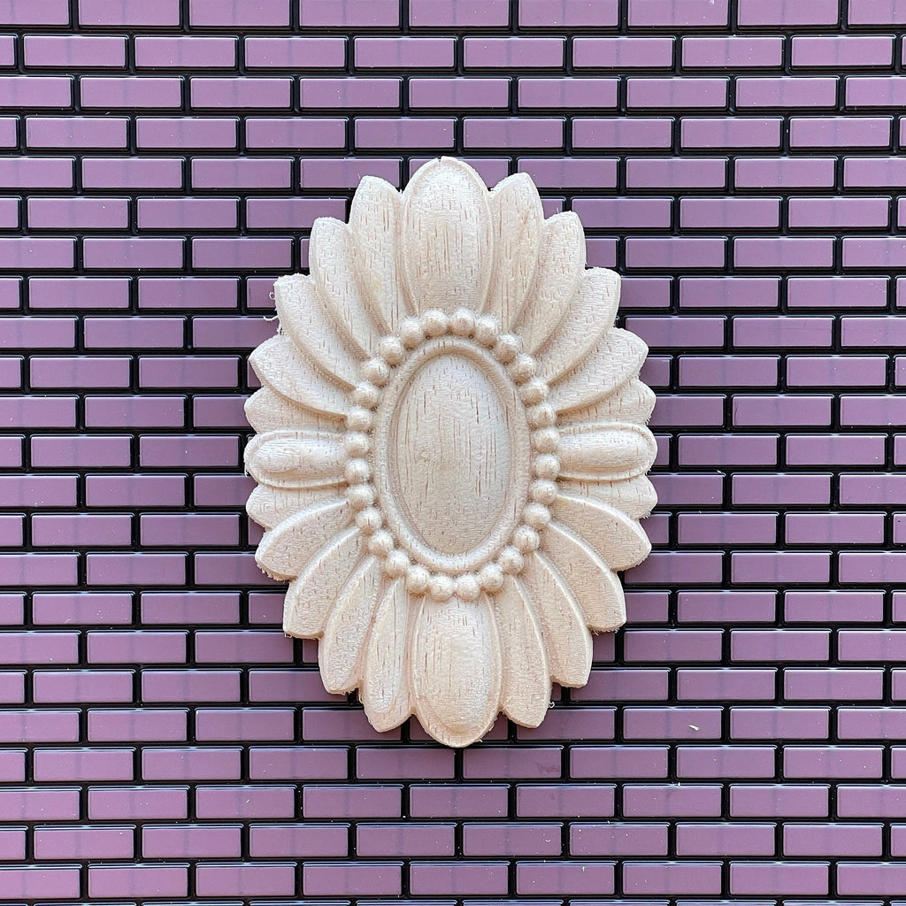 1:12 scale miniature unfinished oval floral ceiling rose with a beaded center, large, shown on a purple brick wall