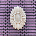 1:12 scale miniature unfinished oval floral ceiling rose with a beaded center, large, shown on a purple brick wall