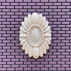 1:12 scale miniature unfinished oval floral ceiling rose with a beaded center, large, shown on a purple brick wall
