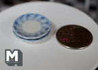 1:12 scale miniature ceramic small plates with blue petal pattern, set of 2, blue and white, stacked beside a coin