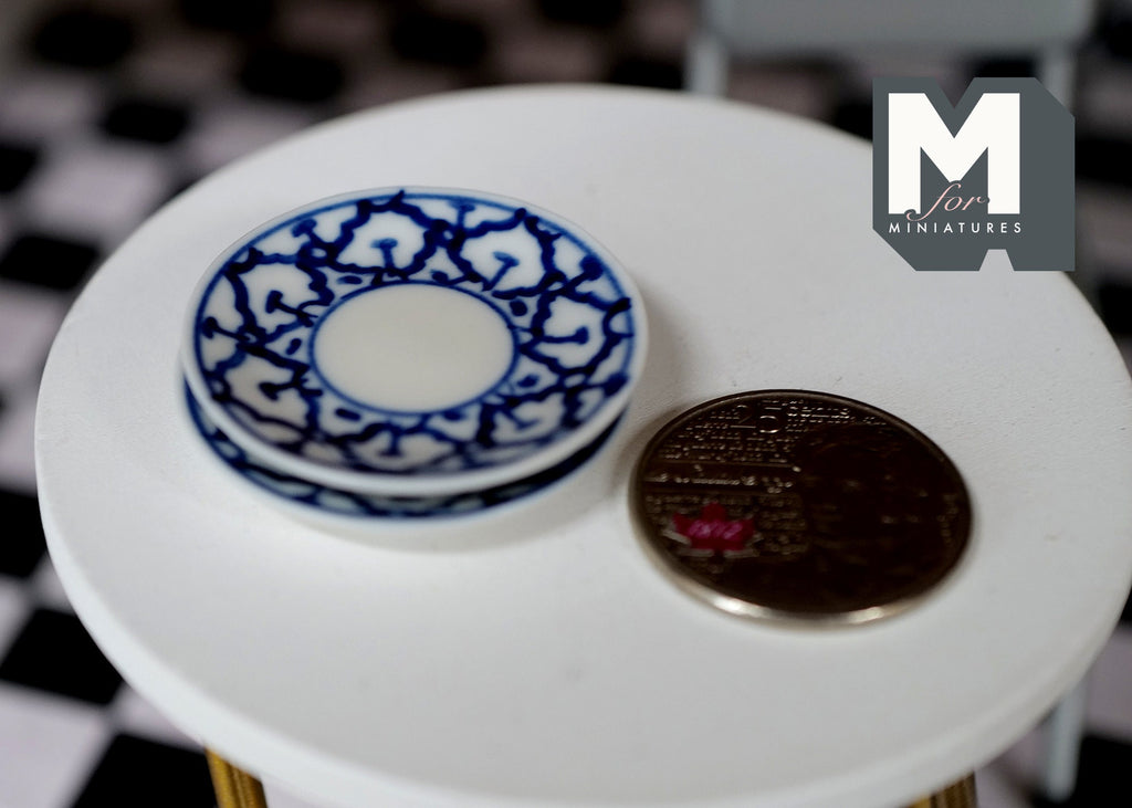 1:12 scale miniature round plates in white with blue lace pattern rim, set of 2, on a white table beside a coin