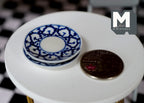 1:12 scale miniature round plates in white with blue lace pattern rim, set of 2, on a white table beside a coin