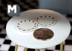 1:12 scale miniature ceramic small polka dot plates in white with red and green dots, set of 2, beside a coin