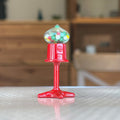 1:12 scale miniature red metal tabletop gumball machine with clear globe of colorful gumballs, on a tabletop