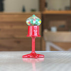 1:12 scale miniature red metal tabletop gumball machine with clear globe of colorful gumballs, on a tabletop