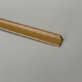 Miniature wood cove cornice molding for ceilings, natural unfinished wood, close-up of the angled profile end on a white surface