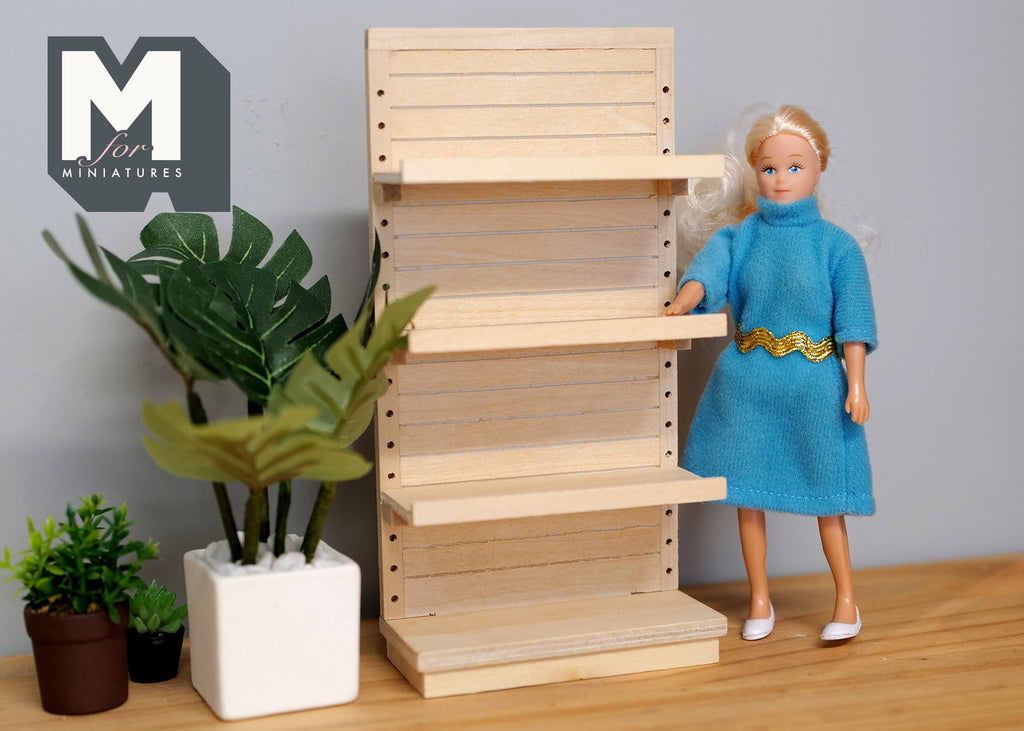 1:12 scale miniature unpainted store display shelf kit with 4 tiers and adjustable shelves, shown beside a doll