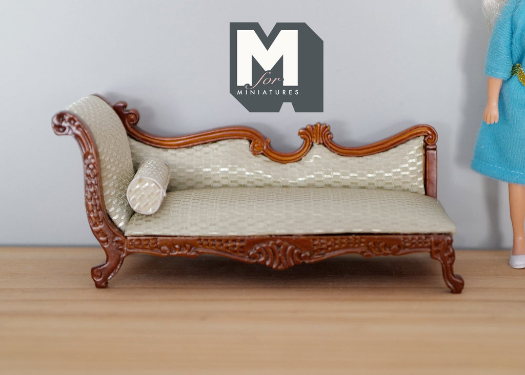 1:12 scale miniature upholstered chaise lounge in cream and brown with bolster pillow and carved frame, on a wood floor