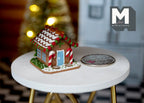 1:12 scale miniature gingerbread house in white and brown with candy cane trim and a blue door, beside a coin