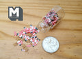 1:12 scale miniature glass candy jar with red, white and green Christmas candies spilling out, shown beside a coin