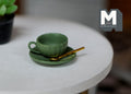 1:12 scale miniature green cup and saucer with gold spoon, large, set of 3, shown on a round white table