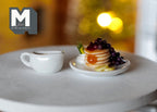 1:12 scale miniature pancake stack with blueberry jam and banana on a plate with white syrup jug, on a round table