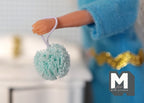 1:12 scale miniature bath sponge pouf with loop in mint green, shown hanging from a doll's hand