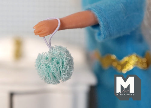 1:12 scale miniature bath sponge pouf with loop in mint green, shown hanging from a doll's hand