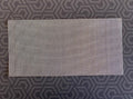 Rectangular sheet of fine stainless steel wire mesh on a dark patterned background