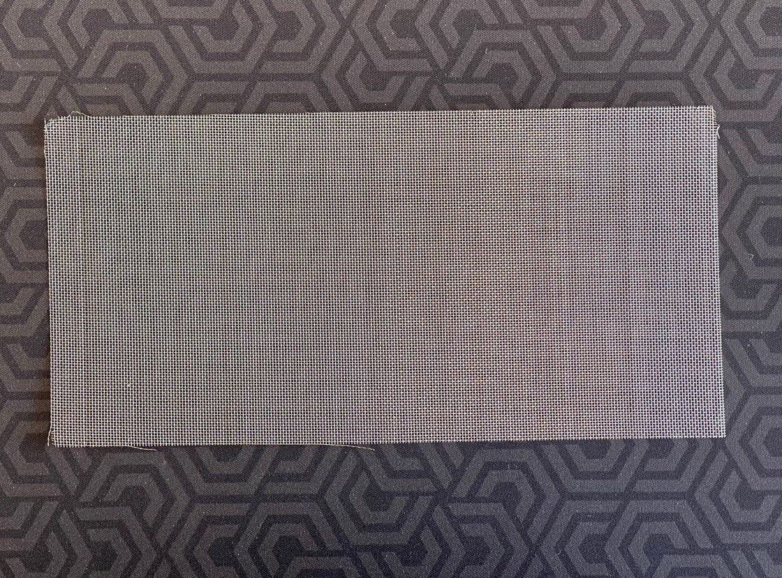 Rectangular sheet of fine stainless steel wire mesh on a dark patterned background