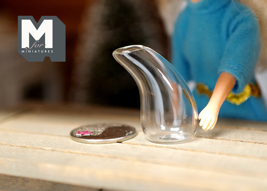 1:12 scale miniature clear glass wine decanter in a swan shape, shown on a table beside a coin and a doll hand