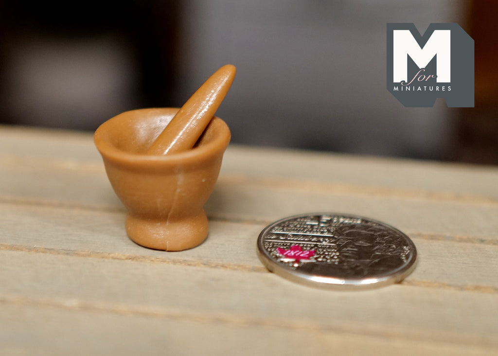 1:12 scale miniature stone look mortar and pestle in warm tan, shown on a wood table beside a coin for scale