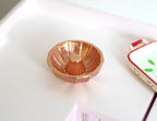 1:12 scale miniature metal bundt cake pan in copper with fluted sides and center tube, on a white kitchen counter
