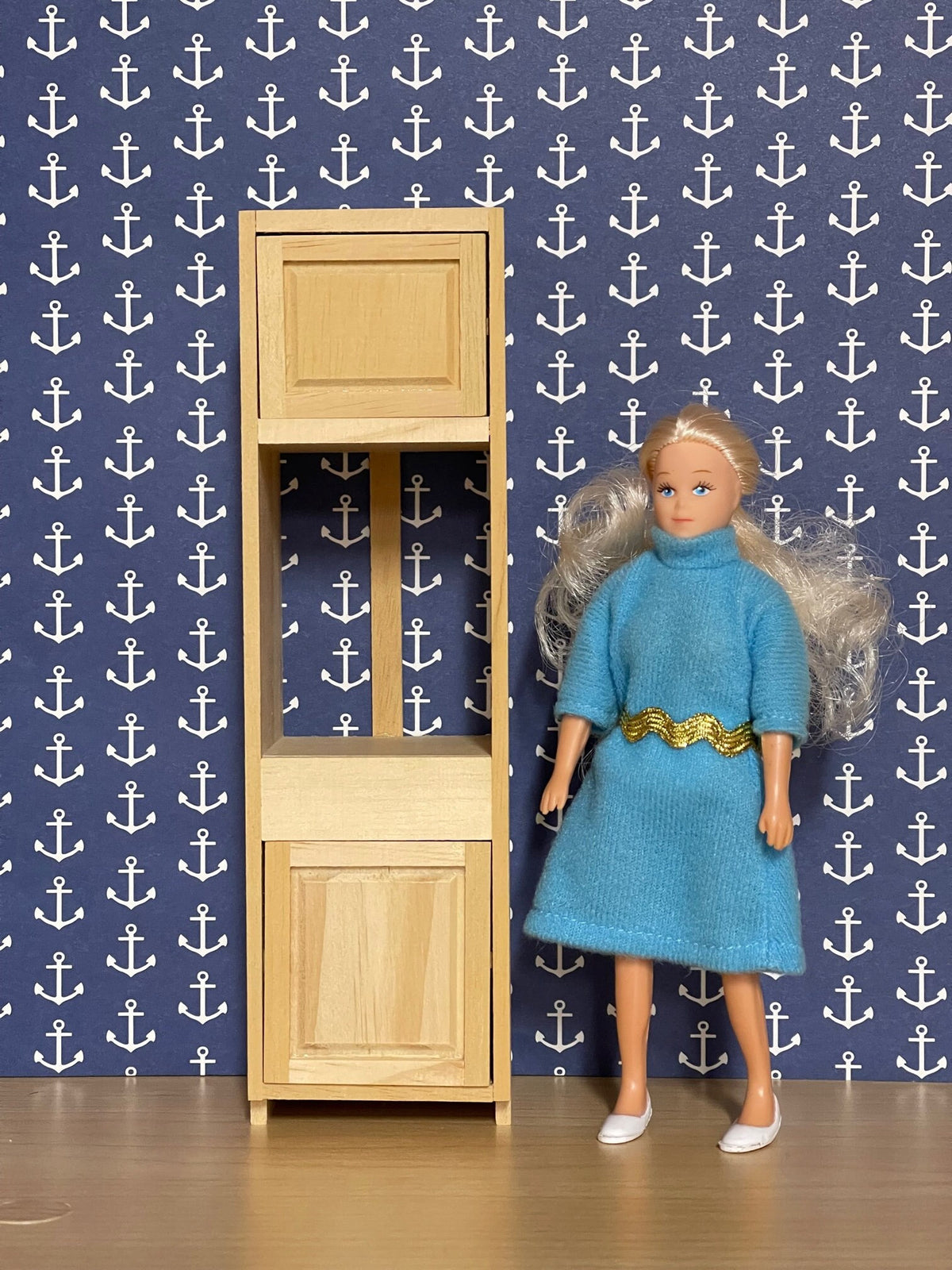 1:12 scale miniature wood oven cabinet kit, semi assembled tall unit with upper and lower doors, shown beside a doll