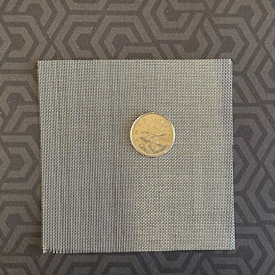 Square sheet of fine stainless steel wire mesh with a coin on top for size