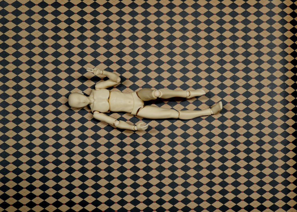 1:12 scale miniature black and tan harlequin diamond peel and stick flooring paper, shown with a wooden artist figure