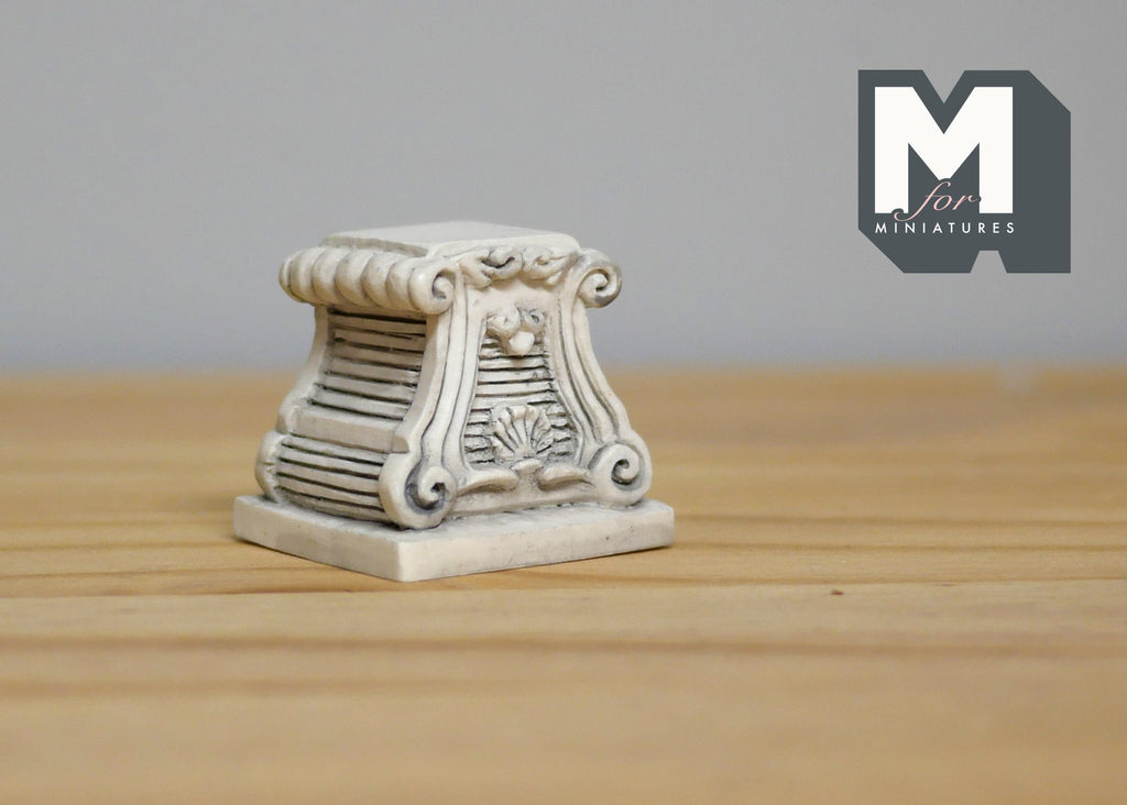 1:12 scale miniature scroll pedestal base in gray with carved detail, shown on a wood table