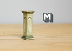 1:12 scale miniature garden pedestal plant stand in gray green with a square column shape, on a wood table