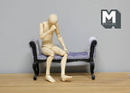 1:12 scale miniature upholstered chaise bench in lavender fabric with black carved wood frame, shown with a seated figure