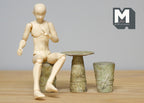 1:12 scale miniature stone look garden table and stools in gray, set of 3, shown with a seated artist figure