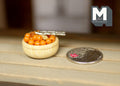 1:12 scale miniature basket of nuts with metal nutcracker, shown on a wood table beside a coin for scale