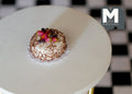 1:12 scale miniature strawberry and blueberry cake with white frosting and sprinkles, shown on a round white table