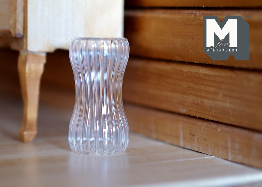 1:12 scale miniature ribbed glass vase with a curved hourglass shape, clear, shown on a white surface by wood furniture