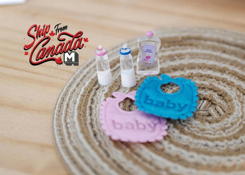 1:12 scale miniature baby feeding set of 5 with bottles, pink and blue bibs and baby oil, shown on a woven rug