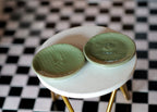 1:12 scale miniature ceramic round plates in green with a ribbed leaf texture, set of 2, on a white round table