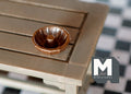 1:12 scale miniature bronze bundt cake pan with fluted sides and center tube, shown on a wood table