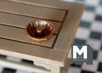 1:12 scale miniature bronze bundt cake pan with fluted sides and center tube, shown on a wood table