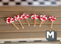 1:12 scale miniature red and white swirl lollipops on sticks, set of 6, shown in a row on a wood table